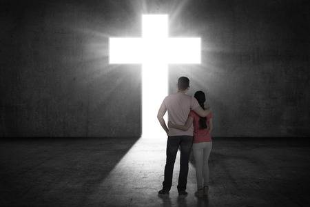 49598634-young-couple-looking-the-shining-cross-on-the-wall-religious-concept